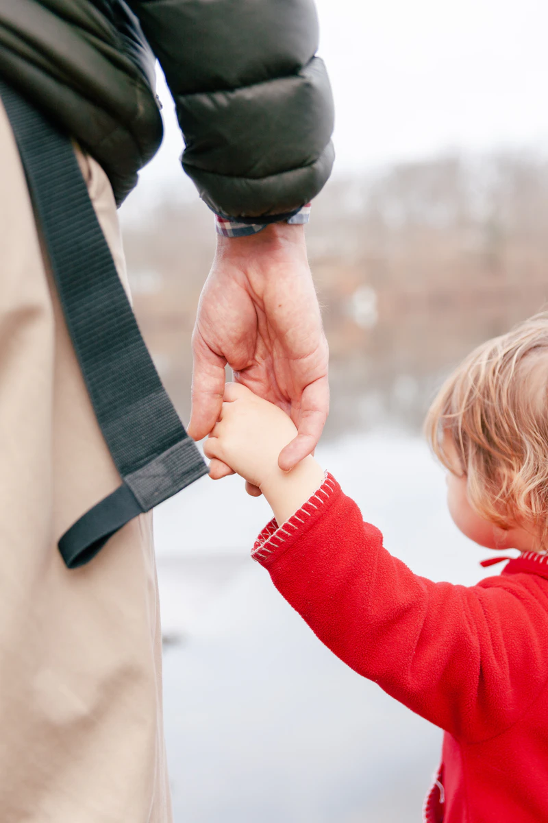 Parent holding a young child by the hand